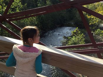 Rear view of girl looking away while standing on bridge
