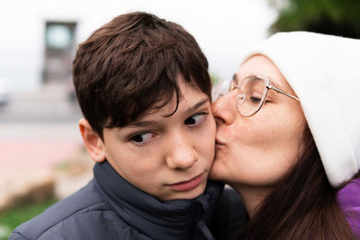 Teenager embarrassed by his mother's kiss on a cold day