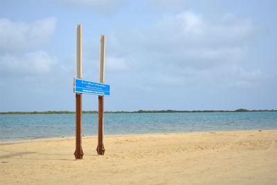 Signboard on beach against cloudy sky