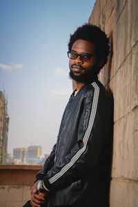 Portrait of young man standing against wall