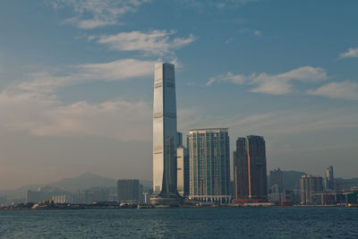 Sea by modern buildings against sky in city