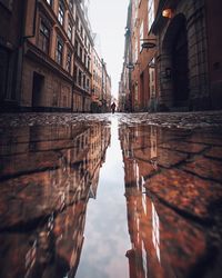 Reflection of buildings in puddle on canal