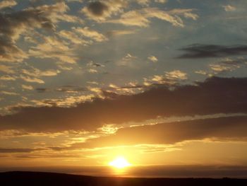 Low angle view of sun shining in sky during sunset