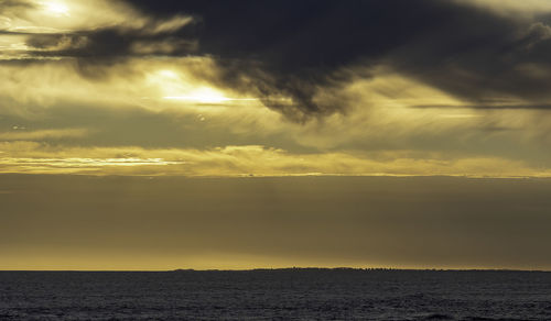 Scenic view of sea against dramatic sky during sunset