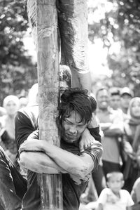 Woman holding hands while standing on tree trunk