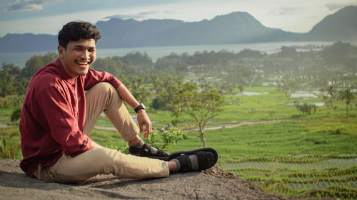 Portrait of young man sitting on field