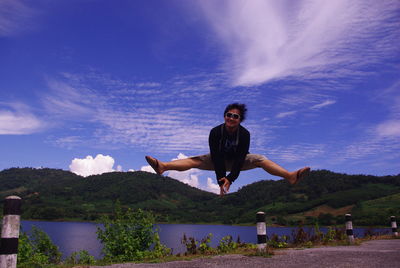 Full length of man jumping against sky and mountain