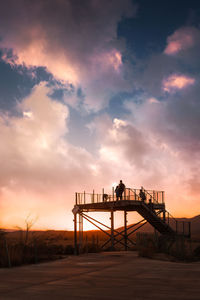 Man standing on bridge against sky during sunset