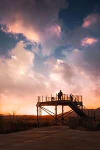 People on observation point against sky during sunset