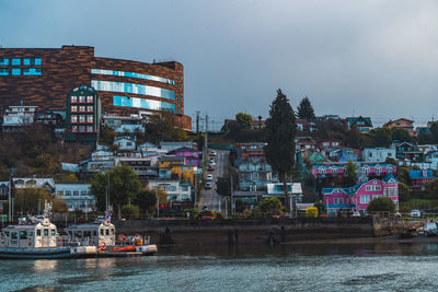 Buildings by river against sky