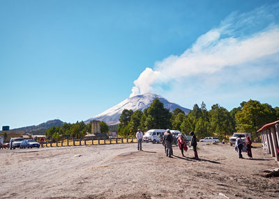 People on road by mountains against sky