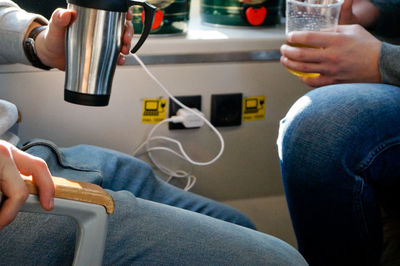 Midsection of people having drinks while traveling in train