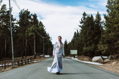 Woman standing by trees against sky