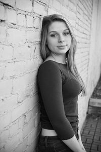 Portrait of young woman leaning against wall