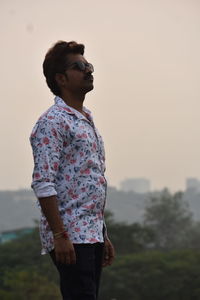Side view of young man looking away against sky during sunset, and evening skay he thinking some pos