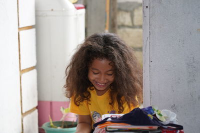 Young woman smiling while sitting against wall