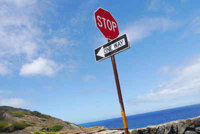 Low angle view of road sign against cloudy sky