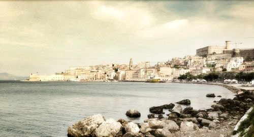 Buildings by sea against sky