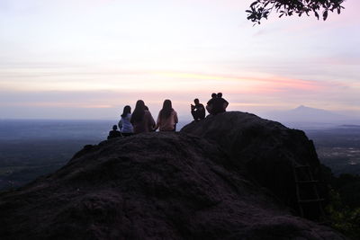 People sitting on rocks against mountain