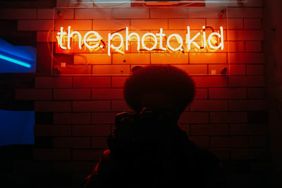 Rear view of girl standing against illuminated building