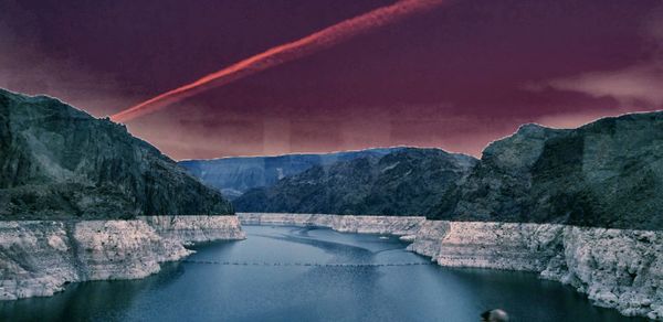 Scenic view of dam and mountains against sky