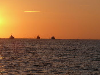 Silhouette boat sailing on sea against sky during sunset