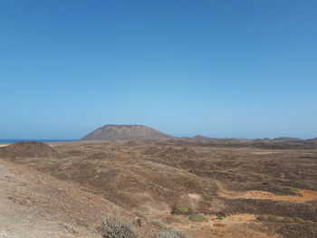 Scenic view of desert against clear blue sky