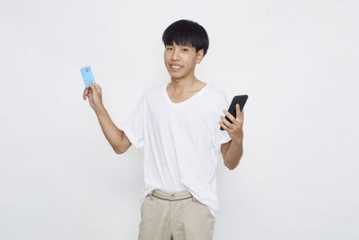 Young man using mobile phone against white background