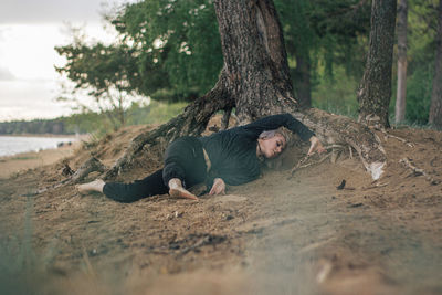 Full length of man lying on tree trunk