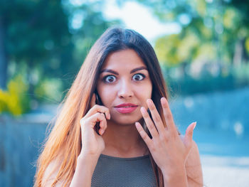 Portrait of shocked woman talking on mobile phone