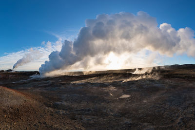 Smoke emitting from volcanic landscape against sky