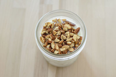 High angle view of almonds on oatmeal in jar at wooden table