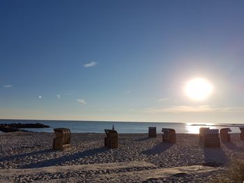 Hooded chairs at beach against sky on sunny day