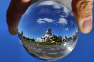Midsection of person holding glass building against blue sky