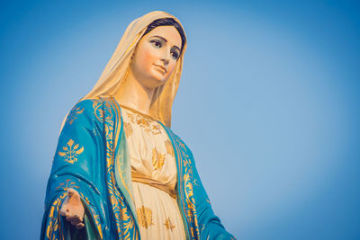 Low angle view of woman standing against blue sky