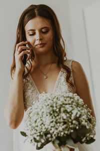Portrait of a happy caucasian bride with a bouquet of boutonnieres and a mobile phone.