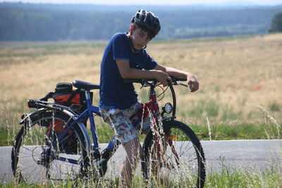 Portrait of teenage boy with bicycle on field