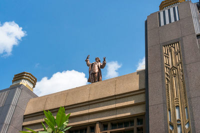 Low angle view of statue against building in city against sky