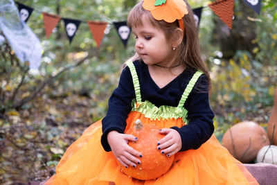 Halloween. cute girl in pumpkin costume with pumpkin outdoor, having fun, celebrating halloween