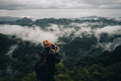 Man photographing on mountain against sky