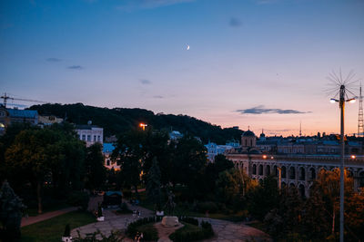 Street amidst buildings against sky at sunset