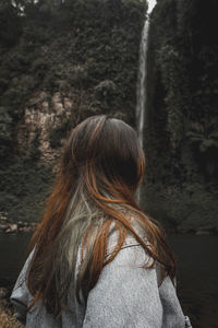 Rear view of woman standing against waterfall