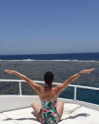 Rear view of woman against sea against clear sky