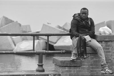 Men sitting on railing against water