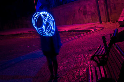 Midsection of woman standing by illuminated light at night