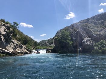 Scenic view of river by mountains against sky