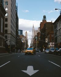 Yellow taxi on city street with chrysler building in background