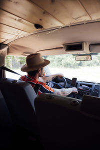 Side view of male traveler sitting on driver seat in van and enjoying road trip in summer