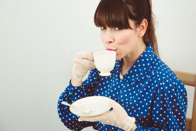 Close-up of woman holding coffee cup against white background