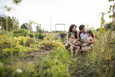 Family on field against clear sky at community garden